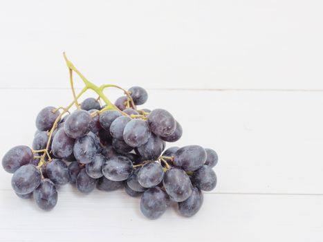Purple grapes bunch on white wooden table with copyspace