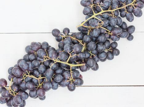 Purple grapes on white wooden table with copyspace. Flat lay or top view