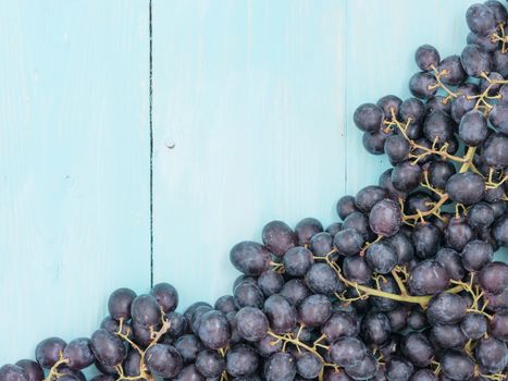 Purple grapes on soft blue wooden table with copyspace. Flat lay or top view