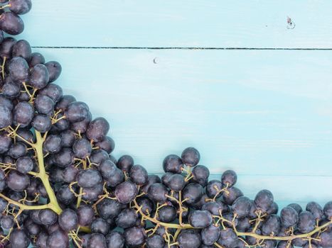 Purple grapes on soft blue wooden table with copyspace. Flat lay or top view