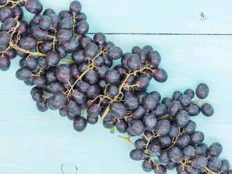 Purple grapes on soft blue wooden table with copyspace. Flat lay or top view