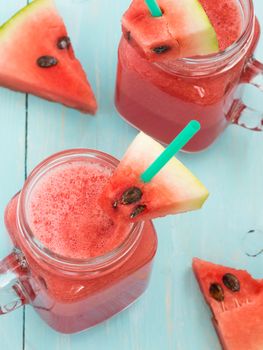 Watermelon smothie and slices on soft blue wooden background. Vertical