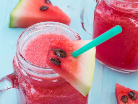 Watermelon smothie and slices on soft blue wooden background