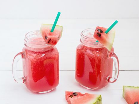 Watermelon smothie and slices on white wooden background