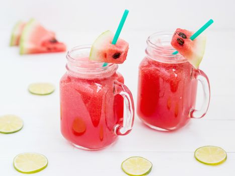 Watermelon smothie and slices on white wooden background