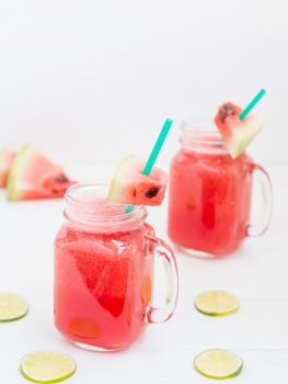 Watermelon smothie and slices on white wooden background. Vertical