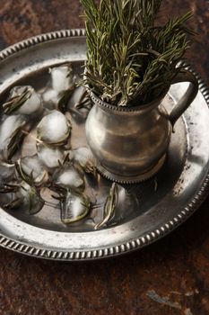 Rosemary in the vase and ice cubes on the dark background