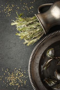 Rosemary in the vase with ice cubes in the metal plate top view