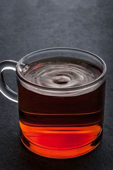 Glass cup of tea on the dark stone table