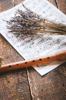 Flute with notes and lavender on the wooden table vertical