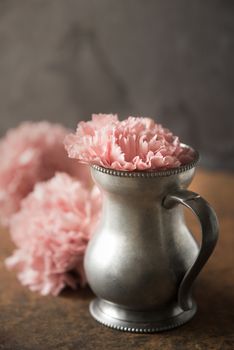 Carnation in the metal vase on the stone table
