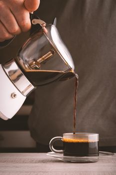 Man pouring coffee into a glass cup vertical