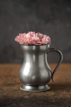 Carnation in the metal vase on the stone table vertical