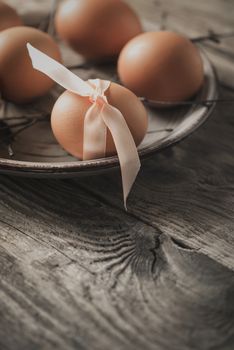 Eggs with  ribbon and branches on the wooden table vertical