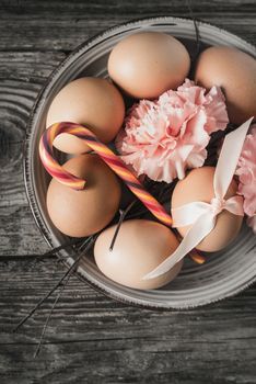 Eggs with ribbon , branches , flowers and candy on the wooden table vertical
