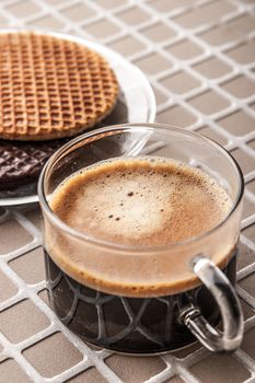 Wafers with cup of coffee on the relief background vertical