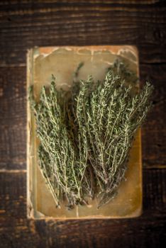 Old cook book with thyme on the wooden table vertical