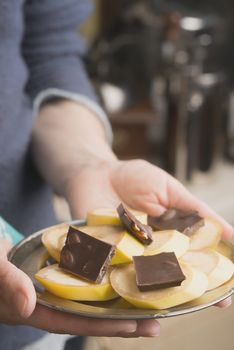 Banana and chocolate slices on the plate in the hand vertical