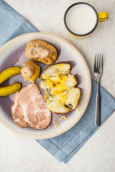 Baked potatoes with meat and pickles on the ceramic plate