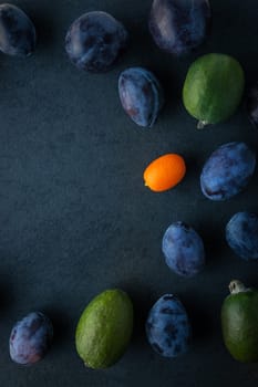 Plums and feijoa on the dark table  vertical