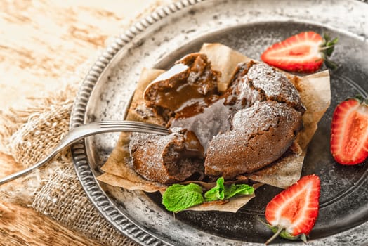 Chocolate fondant with mint and strawberry on the old metal plate