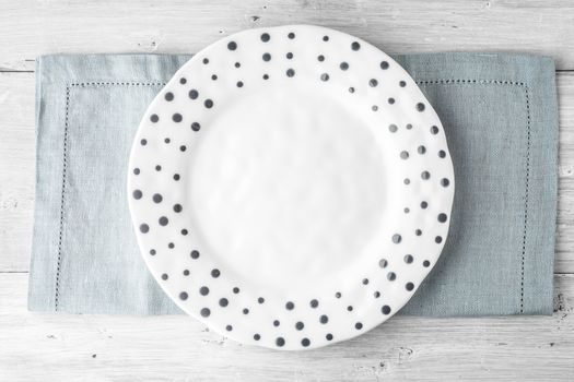 White plate with blue dot on the white wooden table