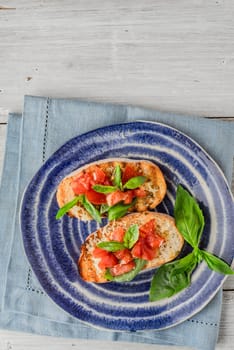 Bruschetta with tomatoes and basil on the ceramic plate vertical