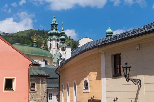 Old houses in the city Banska Stiavnica, former mining city, which is a part of UNESCO World Heritage Site. Towers of the churches. Summer sky with white clouds.