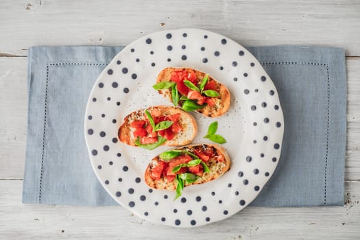 Bruschetta with tomatoes and basil on the ceramic plate top view