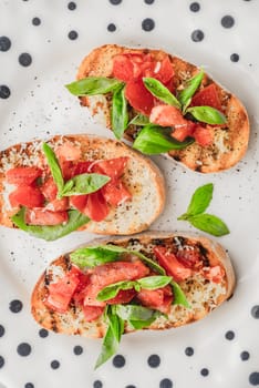 Bruschetta with tomatoes and basil on the ceramic plate