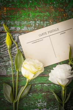 White flowers with postcard on the  wooden table vertical