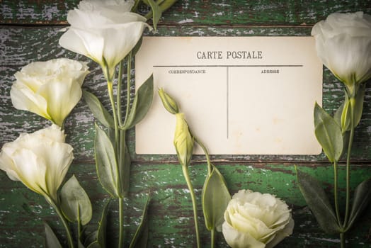 White flowers with postcard on the shabby wooden table