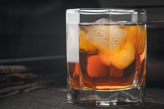 Whiskey with ice  and blurred newspaper on the wooden table