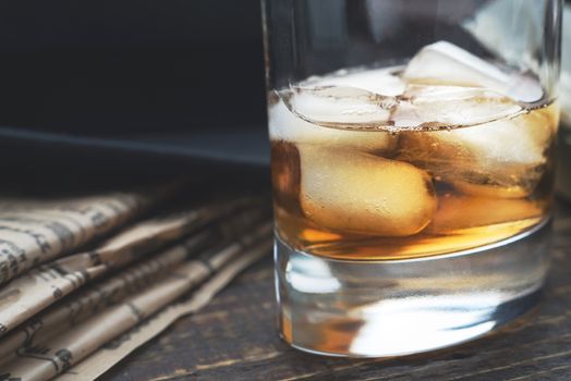 Whiskey with ice  and blurred newspaper on the horizontal