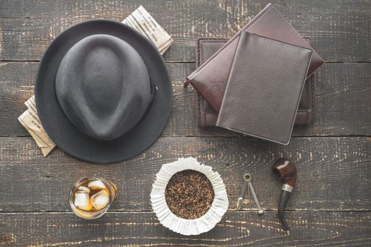 Glass of whiskey , pipe  , hat and newspaper on the wooden table top view