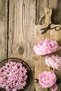 Peonies and plate with flowers on the wooden table vertical
