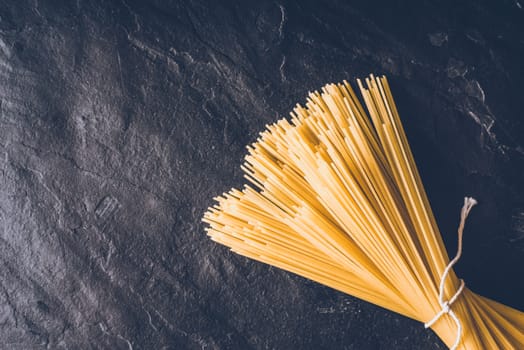 Raw spaghetti on the black stone background top view