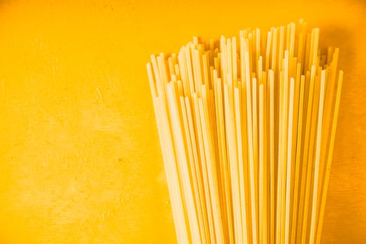 Raw spaghetti on the yellow background horizontal