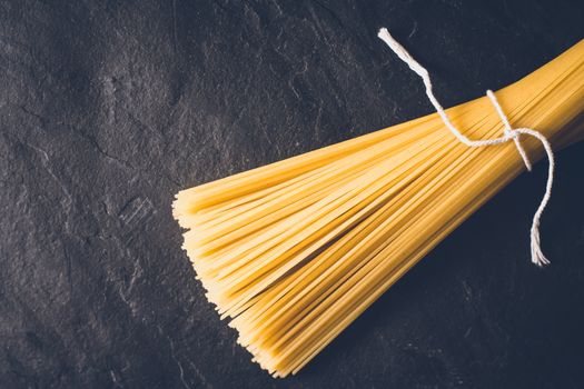 Raw spaghetti on the black stone background