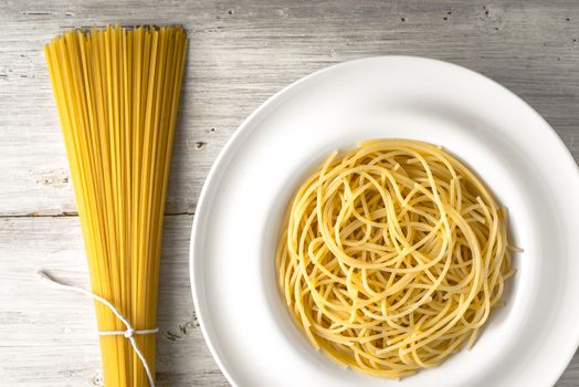 Raw and cooked spaghetti on the white wooden table horizontal