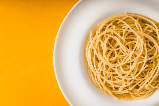 Spaghetti  on the white plate on the yellow background top view