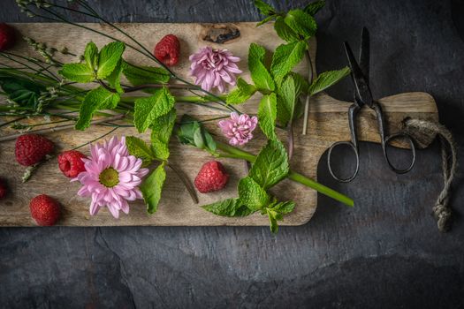 Flowers  , raspberries and mint on the wooden board
