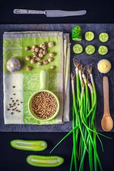 Green vegetables with seasoning on the dark stone background vertical