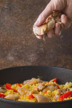 Adding black chicken in the pan with rice and bell pepper vertical