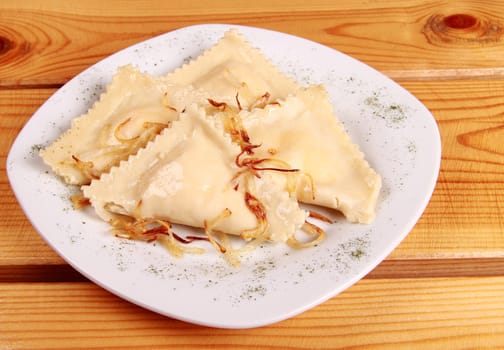 Cooked raviolli with mushrooms on a shiny white plate