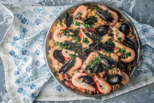 Paella in the metal plate on the  beautiful napkin top view