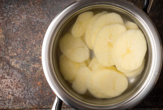 Sliced potatoes in the metal pot with water