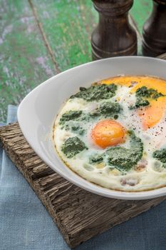 Florentine eggs with pureed spinach on the wooden table vertical