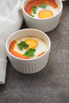 Eggs baked with tomatoes and parsley in the ramekins vertical