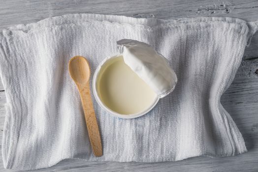 Natural yogurt with spoon and napkin on white wooden table
